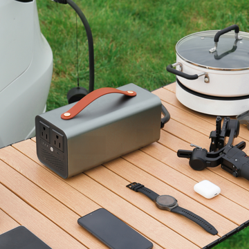 ortiPower portable power station placed on a wooden table, powering multiple outdoor devices such as a smartwatch, phone, and cooking pot, highlighting its versatility and functionality.